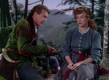 Movie still from “Unconquered” (1947), directed by Cecil B. DeMille – A man and a woman sitting on the ground in front of a forest; Medium shot, Over the shoulder angle