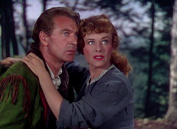 Movie still from “Unconquered” (1947), directed by Cecil B. DeMille – An older man and a younger woman embracing each other in front of a forest; Close Up shot, Low angle