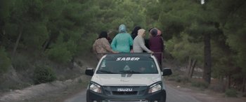 Movie still from “Under the Fig Trees” (2021), directed by Erige Sehiri – A group of women riding on the back of a car; Extreme Wide shot, High angle