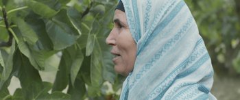 Movie still from “Under the Fig Trees” (2021), directed by Erige Sehiri – A person wearing a headscarf; Close Up shot, Over the shoulder angle
