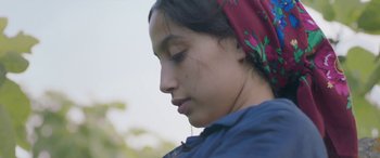 Movie still from “Under the Fig Trees” (2021), directed by Erige Sehiri – A woman with a red head scarf is looking to the side; Close Up shot, Low angle