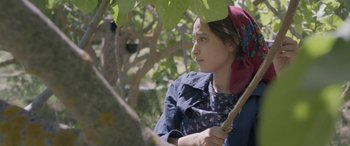 Movie still from “Under the Fig Trees” (2021), directed by Erige Sehiri – A young girl holding a stick under an umbrella; Medium shot, Low angle