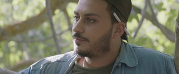 Movie still from “Under the Fig Trees” (2021), directed by Erige Sehiri – A person wearing a hat; Close Up shot, Low angle