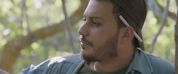 Movie still from “Under the Fig Trees” (2021), directed by Erige Sehiri – A person wearing a hat; Close Up shot, Low angle