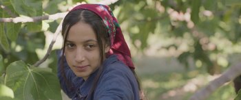 Movie still from “Under the Fig Trees” (2021), directed by Erige Sehiri – A young woman wearing a head scarf poses for a picture; Close Up shot, High angle