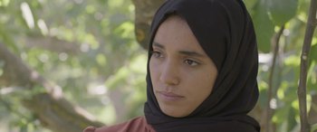 Movie still from “Under the Fig Trees” (2021), directed by Erige Sehiri – A person wearing a headscarf; Close Up shot, Low angle