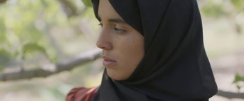 Movie still from “Under the Fig Trees” (2021), directed by Erige Sehiri – A person wearing a headscarf; Close Up shot, Over the shoulder angle