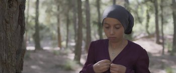 Movie still from “Under the Fig Trees” (2021), directed by Erige Sehiri – A woman in a purple shirt and a black hat; Close Up shot, High angle