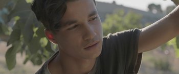 Movie still from “Under the Fig Trees” (2021), directed by Erige Sehiri – A man's face with trees in the background; Close Up shot, Low angle