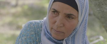 Movie still from “Under the Fig Trees” (2021), directed by Erige Sehiri – An older woman wearing a headscarf looking at the camera; Close Up shot, Over the shoulder angle