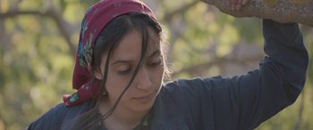 Movie still from “Under the Fig Trees” (2021), directed by Erige Sehiri – A woman with a red head band is looking down; Close Up shot, Low angle