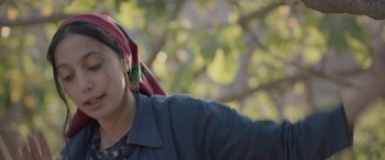 Movie still from “Under the Fig Trees” (2021), directed by Erige Sehiri – A woman wearing a blue jacket and a red head scarf; Close Up shot, Low angle