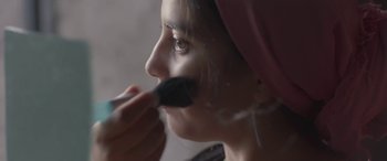 Movie still from “Under the Fig Trees” (2021), directed by Erige Sehiri – A woman is putting make up on her face; Extreme Close Up shot, Low angle