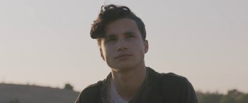Movie still from “Under the Fig Trees” (2021), directed by Erige Sehiri – A young man with dark hair is looking into the distance; Close Up shot, Low angle