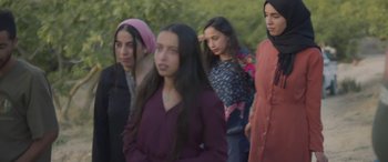 Movie still from “Under the Fig Trees” (2021), directed by Erige Sehiri – A group of young women standing next to each other; Medium shot, Low angle