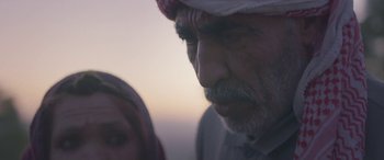 Movie still from “Under the Fig Trees” (2021), directed by Erige Sehiri – An older man and a younger woman looking at one another; Close Up shot, Over the shoulder angle