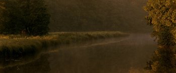 Movie still from “Under the Sun” (1998), directed by Colin Nutley – A grassy area with trees in the background; Extreme Wide shot, Low angle
