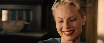 Movie still from “Under the Sun” (1998), directed by Colin Nutley – A woman with red lipstick smiles while wearing headphones; Close Up shot, Overhead angle