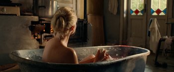 Movie still from “Under the Sun” (1998), directed by Colin Nutley – A woman sitting in a bath tub in front of a fire place; Medium shot, High angle