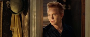 Movie still from “Under the Sun” (1998), directed by Colin Nutley – A young man with blonde spiky hair and blue eyes looking out a window; Close Up shot, Over the shoulder angle