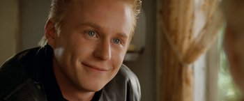 Movie still from “Under the Sun” (1998), directed by Colin Nutley – A person with blue eyes smiling; Close Up shot, Over the shoulder angle