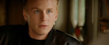 Movie still from “Under the Sun” (1998), directed by Colin Nutley – A person wearing a leather jacket; Close Up shot, Over the shoulder angle