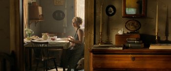 Movie still from “Under the Sun” (1998), directed by Colin Nutley – A woman sitting at a dining room table; Wide shot, Over the shoulder angle