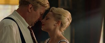 Movie still from “Under the Sun” (1998), directed by Colin Nutley – A man and a woman kissing each other in front of a wall; Close Up shot, Low angle