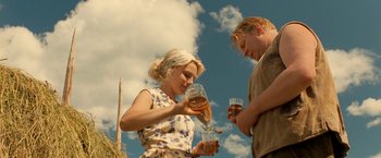 Movie still from “Under the Sun” (1998), directed by Colin Nutley – A woman and a man holding glasses of beer; Medium shot, Low angle