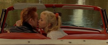 Movie still from “Under the Sun” (1998), directed by Colin Nutley – Two people are kissing in a boat on the water; Close Up shot, High angle