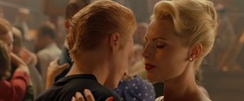 Movie still from “Under the Sun” (1998), directed by Colin Nutley – A man and a woman kissing in front of an audience; Close Up shot, Over the shoulder angle