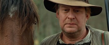 Movie still from “Under the Sun” (1998), directed by Colin Nutley – A person wearing a hat; Close Up shot, Over the shoulder angle