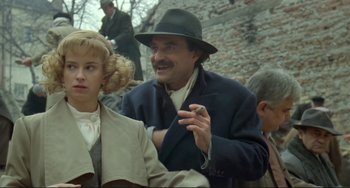 Movie still from “Underground” (1995), directed by Emir Kusturica – A man in a hat smoking a cigarette next to a woman in a suit; Medium shot, Over the shoulder angle