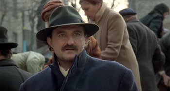 Movie still from “Underground” (1995), directed by Emir Kusturica – A man wearing a green hat and a blue coat; Close Up shot, Over the shoulder angle