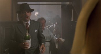 Movie still from “Underground” (1995), directed by Emir Kusturica – A man in a suit and tie holding a bottle of wine; Medium shot, Low angle