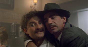 Movie still from “Underground” (1995), directed by Emir Kusturica – A man and a man in a hat are hugging each other; Close Up shot, Low angle