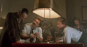 Movie still from “Underground” (1995), directed by Emir Kusturica – A group of men sitting around a pool table; Medium shot, Low angle