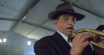 Movie still from “Underground” (1995), directed by Emir Kusturica – A man in a suit and a hat holding a pipe; Close Up shot, Low angle
