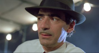 Movie still from “Underground” (1995), directed by Emir Kusturica – A person wearing a hat and a tie; Close Up shot, Low angle