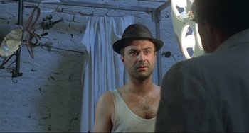 Movie still from “Underground” (1995), directed by Emir Kusturica – A man in a hat looking into a mirror; Close Up shot, Low angle