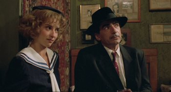 Movie still from “Underground” (1995), directed by Emir Kusturica – A man and a woman sitting next to each other in a room; Close Up shot, Over the shoulder angle