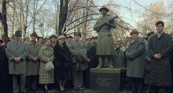 Movie still from “Underground” (1995), directed by Emir Kusturica – A group of people standing around a statue of a man in uniform; Wide shot, Low angle