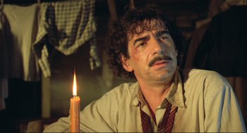 Movie still from “Underground” (1995), directed by Emir Kusturica – A man with a candle in a room; Close Up shot, Low angle
