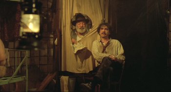 Movie still from “Underground” (1995), directed by Emir Kusturica – Two men are posing for a picture in a room; Medium shot, Low angle