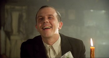 Movie still from “Underground” (1995), directed by Emir Kusturica – A man in a suit smiling for the camera; Close Up shot, Low angle