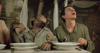Movie still from “Underground” (1995), directed by Emir Kusturica – Two people sitting at a table with plates of food in front of them; Medium shot, Low angle