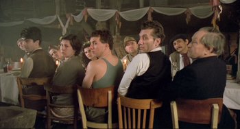 Movie still from “Underground” (1995), directed by Emir Kusturica – A group of people sitting at a table with candles; Medium shot, Low angle