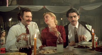 Movie still from “Underground” (1995), directed by Emir Kusturica – A group of people sitting at a table with food; Medium shot, Low angle