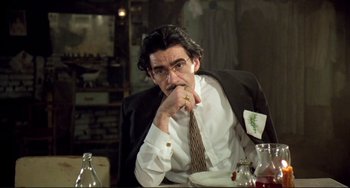 Movie still from “Underground” (1995), directed by Emir Kusturica – A man sitting at a table with his hand under his chin; Medium shot, Low angle