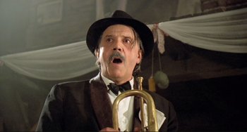 Movie still from “Underground” (1995), directed by Emir Kusturica – A man in a suit and a hat holding a trumpet; Close Up shot, Low angle